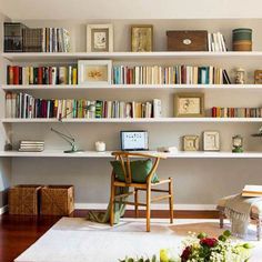 a living room filled with furniture and lots of books on the shelves above it's desk