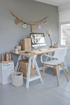 a desk with a computer on top of it in front of a window filled with boxes