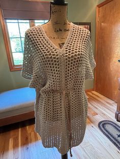 a crocheted top on a mannequin in front of a wooden floor