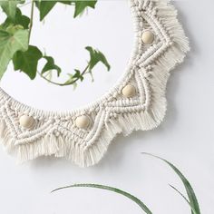 a white circular mirror sitting on top of a table next to a green leafy plant