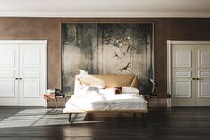 a bed sitting in a bedroom next to a painting on the wall and wooden floors