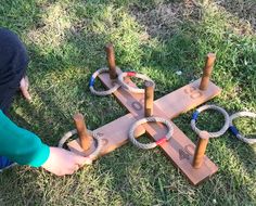 a child is playing with an obstacle made out of wood and rope on the grass