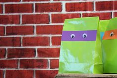 two paper bags decorated like teenage mutant heads are sitting on a table in front of a brick wall