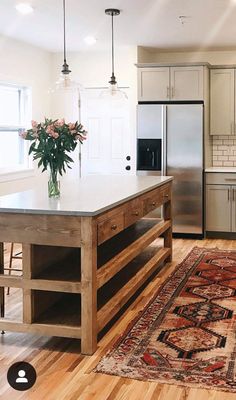 a kitchen with an island, sink and refrigerator in it's center area next to a rug