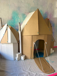 cardboard houses are set up in front of a wall