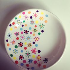 a white plate with multicolored dots and flowers on the rim is sitting on a table