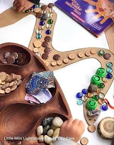 a child is playing with a wooden tray filled with buttons and beads on a table