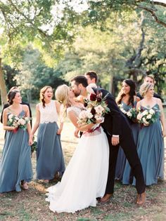 a bride and groom kissing in front of their bridal party