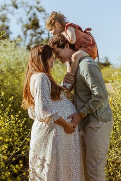 a man and woman holding a child in their arms while standing next to each other