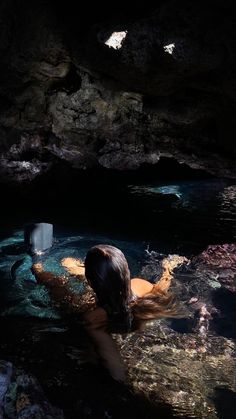 a woman is swimming in the water with her back turned to the camera and holding an object