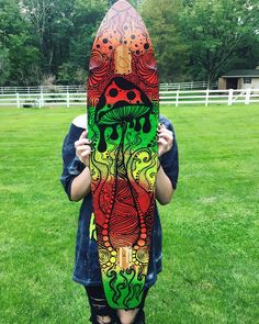 a person holding up a skateboard in front of their face with an artistic design on it