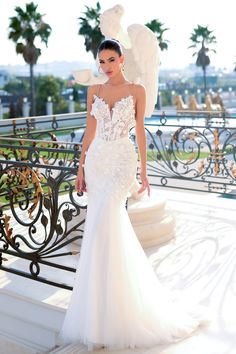 a woman in a white wedding dress standing on stairs with an angel statue behind her