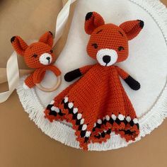 two crocheted stuffed animals sitting on top of a white doily next to each other