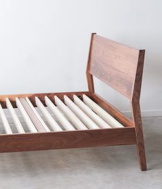 a wooden bed frame with white candles on the bottom and side rails, in front of a wall