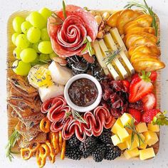 an assortment of cheeses, fruits and meats arranged in a square platter