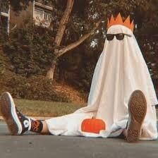 a man laying on the ground next to a white and orange tent with a crown on it