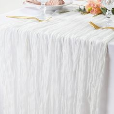 the table is set with white linens and gold place settings for two people to eat