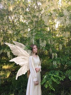 a woman dressed as a fairy standing in front of trees