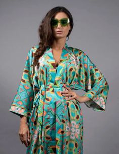 The Nuvula Psychedelic Stars Teal Long Satin Kimono can be worn to lounge, overtop a slip dress for a night out, and pairs perfectly with a matching bikini and flared pants for working out or hanging out by the pool. Timeless style and creativity meet Psychedelic designs in Nuvula’s handmade silk kimonos. This Limited Edition Robe is handcrafted in super soft satin. Wear it to elevate an evening dress with high stiletto heels, slip it on over a swimsuit, or wear it at home as nightwear. Hand-Mad Green Kimono Sleeves Sleepwear For Summer, Summer Sleepwear Kimono With Prints, Green Summer Sleepwear With Kimono Sleeves, Multicolor Summer Sleep Kimono, Green Kimono For Loungewear, Teal Kimono, Pool Wear, Satin Kimono, Duchess Satin