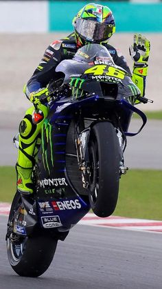 a man riding on the back of a motorcycle down a race track