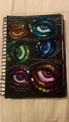 a spiral notebook with an image of four different colored eyeballs on the cover and words written in cursive writing