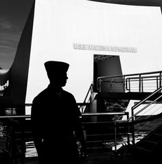 a black and white photo of a man standing in front of the uss san antonio memorial