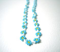 "A gorgeous necklace featuring a chain of delicate forget me nots! Glass seed beads in a bright, light blue surround sweet yellow centres to mimic the beautiful forget-me-not. Each bead has been carefully woven into place using a needle and thread to create this flower necklace that you'll just love to drape around your neck. Perfect for long, sunny summer days and balmy summer nights. This necklace measures approximately 20\" or 49cm long and finished with your choice of clasp! A sterling silve Blue Flower Pendant Beaded Necklace, Blue Beaded Necklace With Flower Pendant, Light Blue Beaded Flower Jewelry, Light Blue Flower-shaped Beaded Jewelry, Handmade Blue Flower Beaded Necklaces, Handmade Blue Flower Beaded Necklace, Blue Beaded Flower Necklace Gift, Blue Beaded Flower Necklace As Gift, Blue Flower Shaped Beaded Necklace For Gift