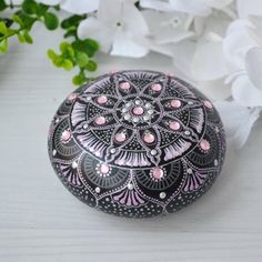 a black and pink painted rock next to white flowers