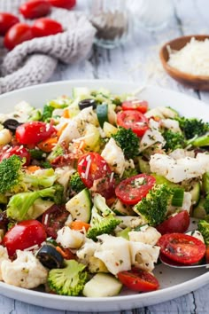 a white bowl filled with pasta and veggies on top of a wooden table