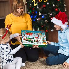 a woman and two children sitting on the floor with a christmas card in front of them