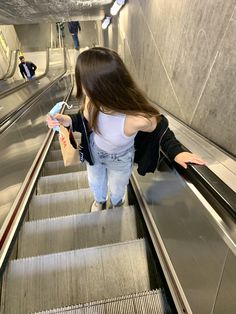 a woman is riding down an escalator with her cell phone in her hand