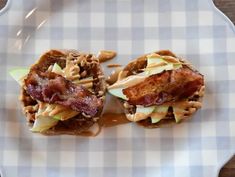 two sandwiches with bacon, apple slices and caramel sauce on a white plate sitting on a wooden table