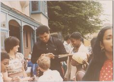 a group of people standing around each other in front of a building and one person holding a baby