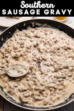 a skillet filled with sausage and gravy on top of a wooden table