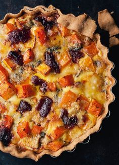 a quiche with cheese, meat and vegetables in it sitting on a table top