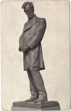 an old black and white photo of a man in a suit standing on a pedestal