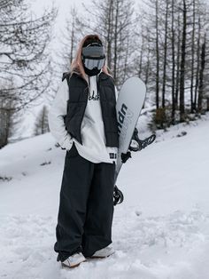 a person standing in the snow holding a snowboard