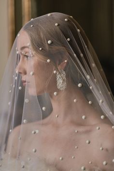 a woman wearing a veil with pearls on it