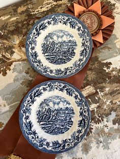 two blue and white plates sitting next to each other on a tablecloth covered surface