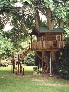 a tree house in the middle of a grassy area with stairs leading up to it