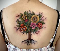 a woman's back tattoo with flowers and leaves