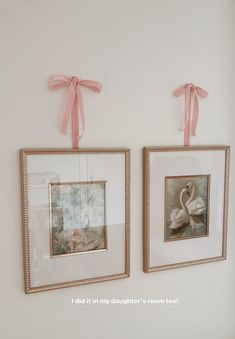 two framed pictures hang on the wall next to each other with pink ribbons tied around them