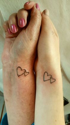 two people with matching tattoos on their arms, both holding each other's hands