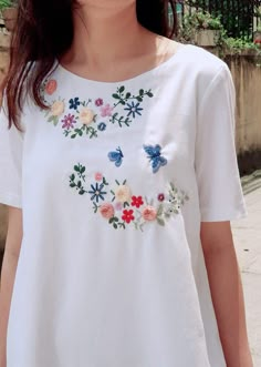 a woman wearing a white shirt with flowers on it