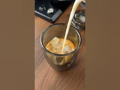 a glass filled with liquid sitting on top of a wooden table next to a stove