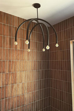 a chandelier hanging from the ceiling in a bathroom with tiled walls and floor