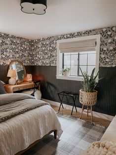 a bed room with a neatly made bed next to a window and a mirror on the wall