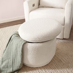 a white chair and ottoman with a green blanket on the floor in front of it