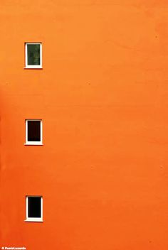 an orange building with three windows and a clock