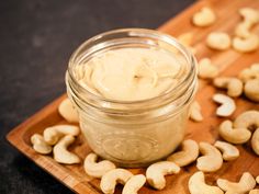 a jar filled with cashews sitting on top of a wooden cutting board